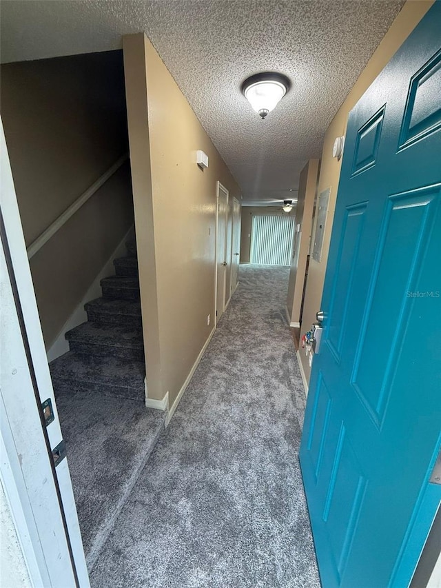 corridor with a textured ceiling and dark carpet