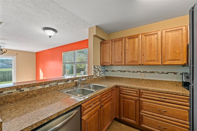 kitchen featuring sink, backsplash, stainless steel dishwasher, kitchen peninsula, and a textured ceiling