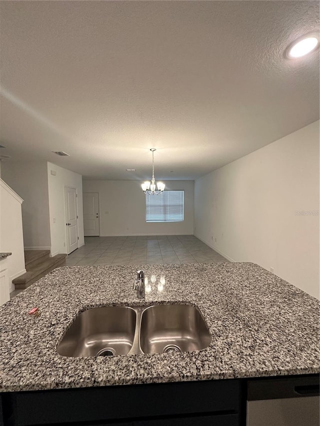 kitchen with stone counters, tile patterned floors, sink, a textured ceiling, and a chandelier