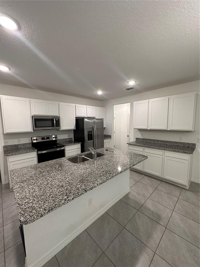 kitchen featuring white cabinetry, a center island with sink, stainless steel appliances, and a textured ceiling