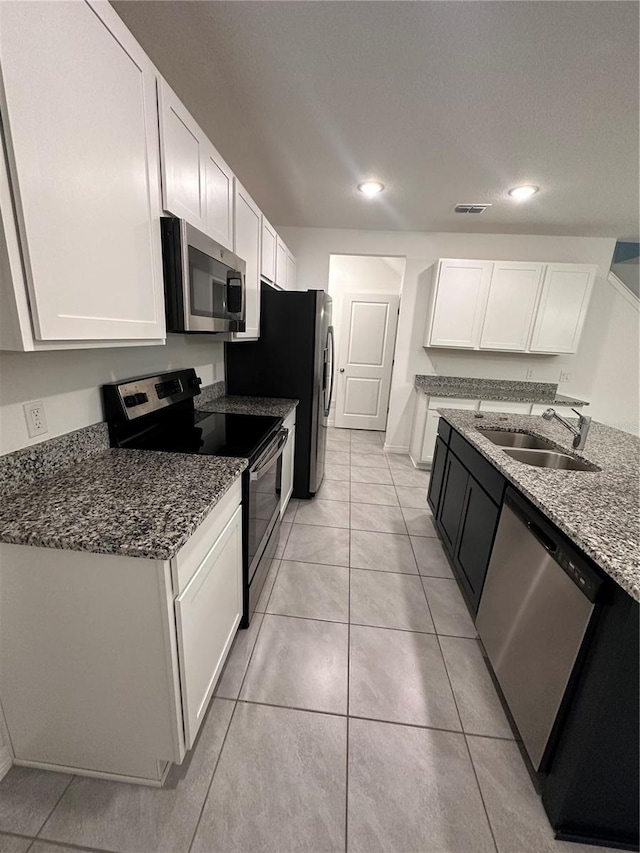 kitchen with white cabinets, sink, stainless steel appliances, and dark stone counters