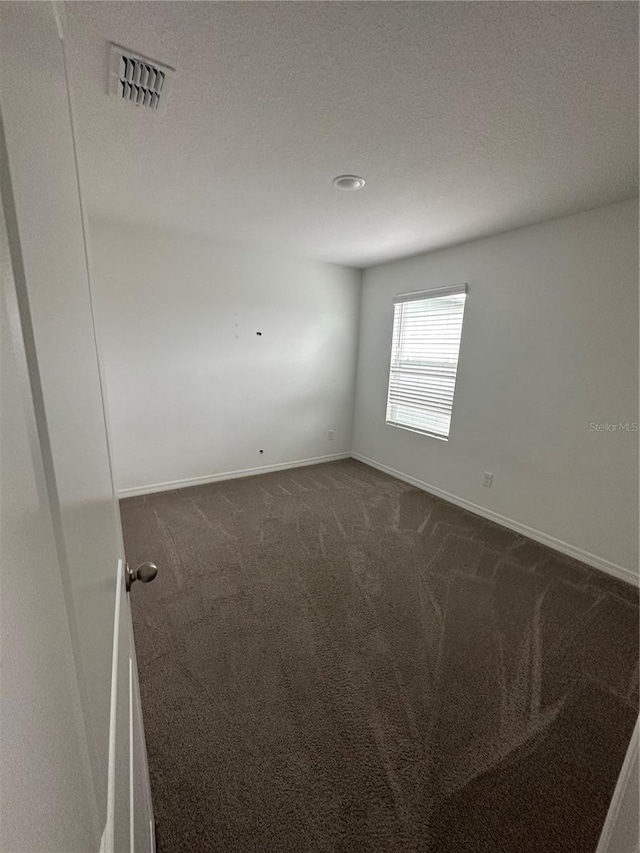 empty room featuring dark colored carpet and a textured ceiling