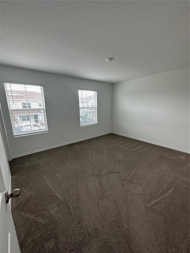 carpeted empty room with a textured ceiling