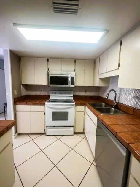 kitchen with tasteful backsplash, appliances with stainless steel finishes, sink, and light tile patterned floors