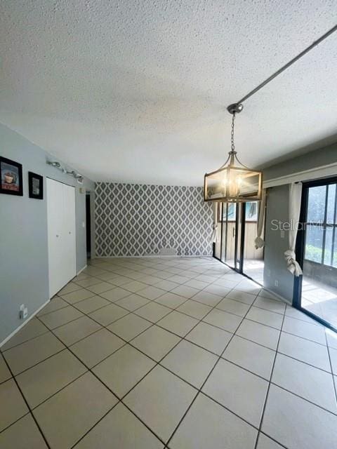 spare room featuring an inviting chandelier, a textured ceiling, and tile patterned flooring