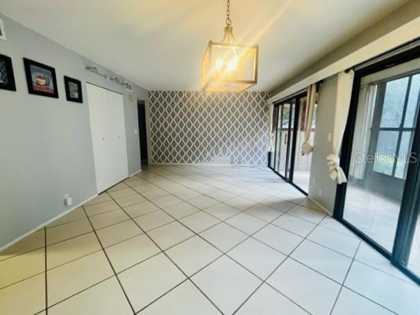 tiled empty room with an inviting chandelier