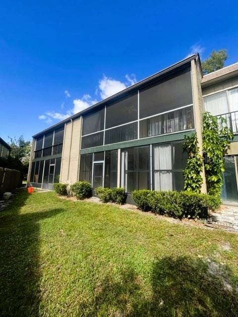 back of property featuring a lawn and a sunroom