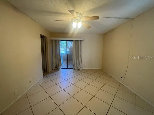 unfurnished room with a textured ceiling, ceiling fan, and light tile patterned floors