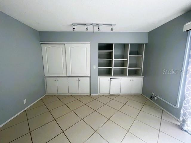 unfurnished bedroom featuring a closet, track lighting, and light tile patterned floors