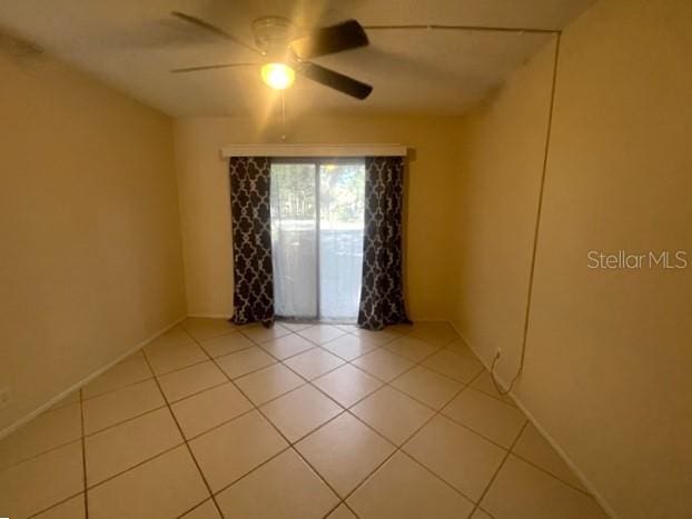 tiled spare room with ceiling fan