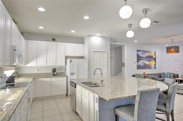 kitchen featuring stainless steel appliances, a center island with sink, white cabinets, hanging light fixtures, and sink