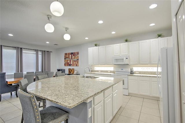 kitchen featuring white cabinetry, sink, hanging light fixtures, white appliances, and an island with sink