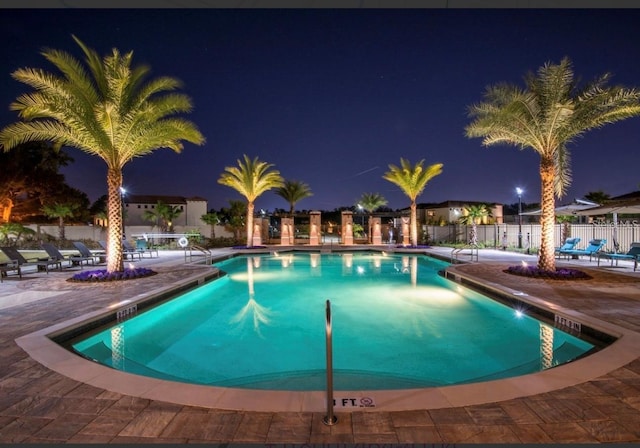 pool at night featuring a patio