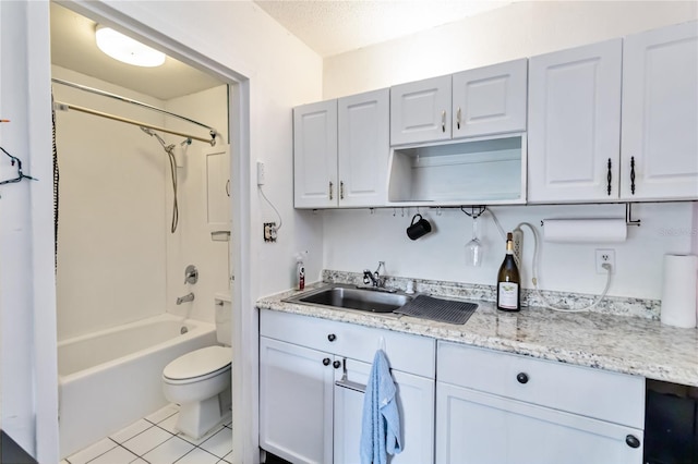 kitchen with sink, light stone countertops, a textured ceiling, white cabinets, and light tile patterned flooring