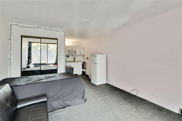 bedroom featuring white refrigerator, dark carpet, and a textured ceiling