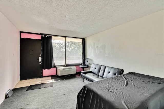 bedroom featuring a wall mounted AC, light carpet, and a textured ceiling