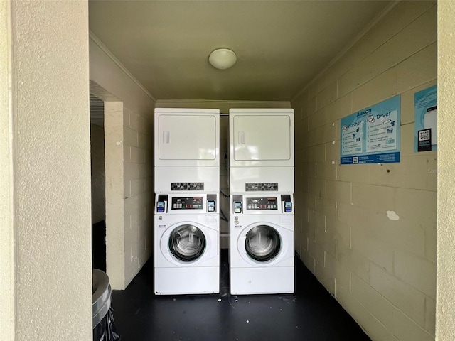 clothes washing area with crown molding and stacked washer and clothes dryer