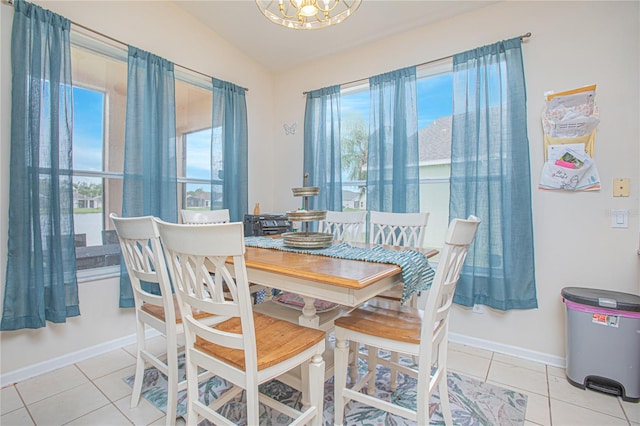 tiled dining room with a notable chandelier and lofted ceiling