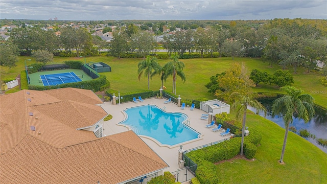 view of pool featuring a patio area, a yard, a water view, and a storage shed