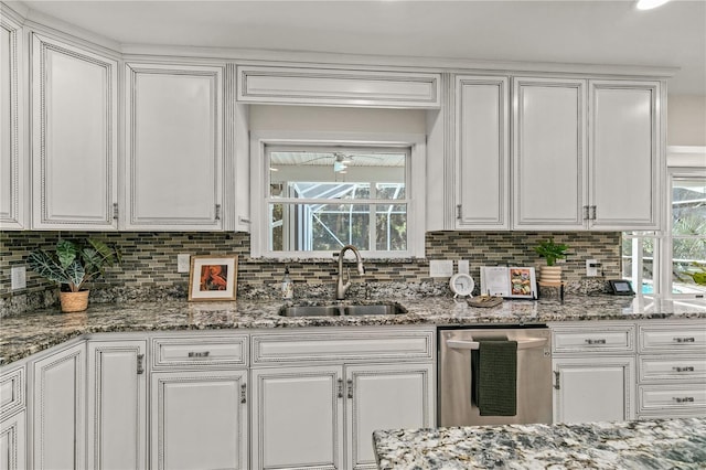 kitchen featuring stainless steel dishwasher, white cabinets, sink, and plenty of natural light