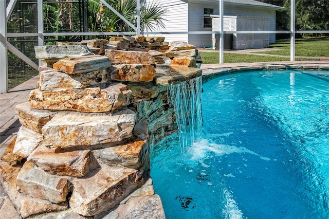 view of swimming pool featuring a lawn and a lanai