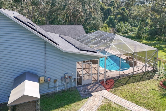 view of swimming pool with glass enclosure, a lawn, and a patio area