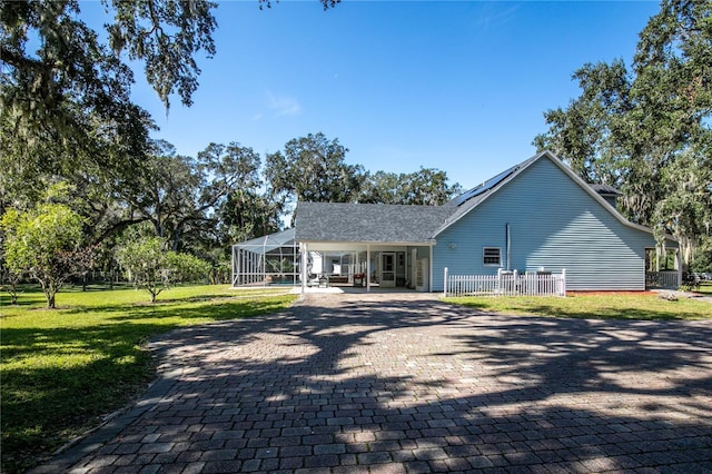 exterior space with a front yard, glass enclosure, and a patio area