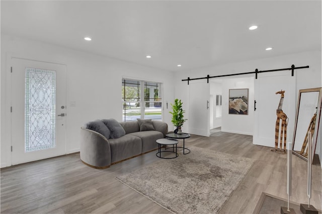 living room with a barn door and light hardwood / wood-style floors