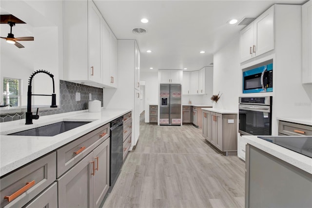 kitchen with stainless steel appliances, sink, gray cabinets, white cabinetry, and light wood-type flooring