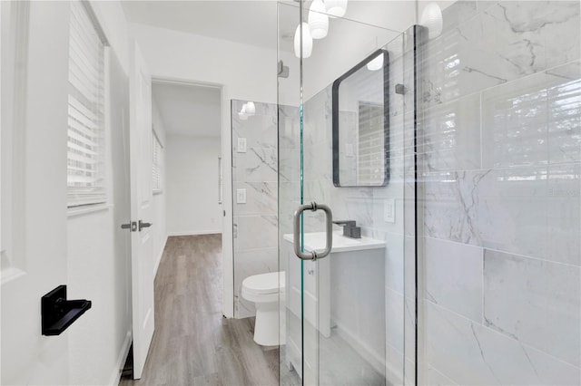 bathroom featuring walk in shower, toilet, and wood-type flooring