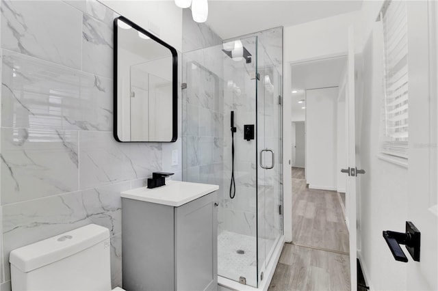 bathroom with tile walls, vanity, an enclosed shower, hardwood / wood-style flooring, and toilet