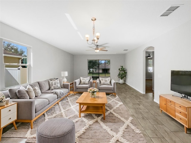 living room with ceiling fan with notable chandelier, a healthy amount of sunlight, and light wood-type flooring