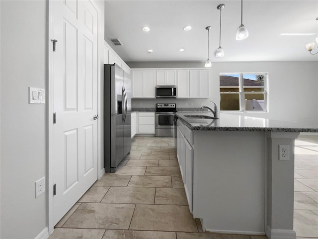 kitchen with white cabinetry, sink, appliances with stainless steel finishes, dark stone countertops, and hanging light fixtures