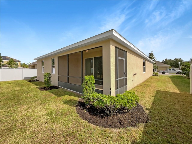 view of side of property with a sunroom and a yard