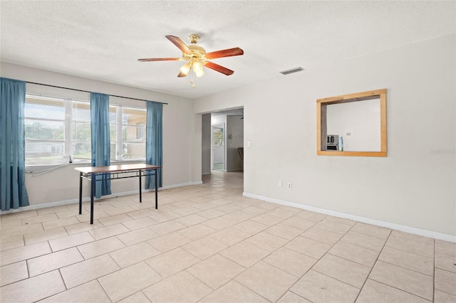 spare room featuring a textured ceiling, ceiling fan, and light tile patterned flooring