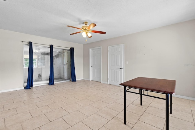 interior space with a textured ceiling, ceiling fan, and light tile patterned floors