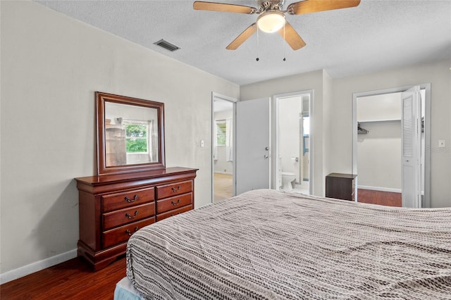 bedroom with ensuite bath, a textured ceiling, dark hardwood / wood-style floors, ceiling fan, and a closet