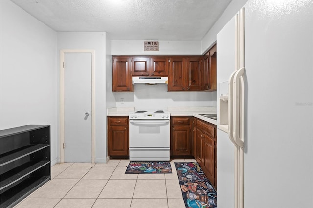 kitchen featuring a textured ceiling, white appliances, and light tile patterned floors