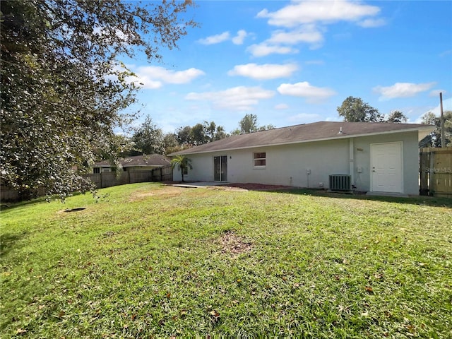 rear view of property with central air condition unit and a lawn