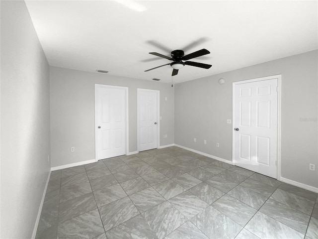 unfurnished bedroom featuring ceiling fan and two closets