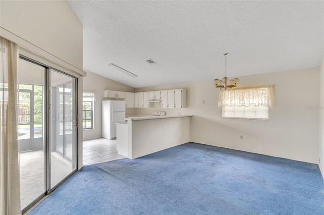 kitchen featuring white cabinets, plenty of natural light, white refrigerator, and kitchen peninsula