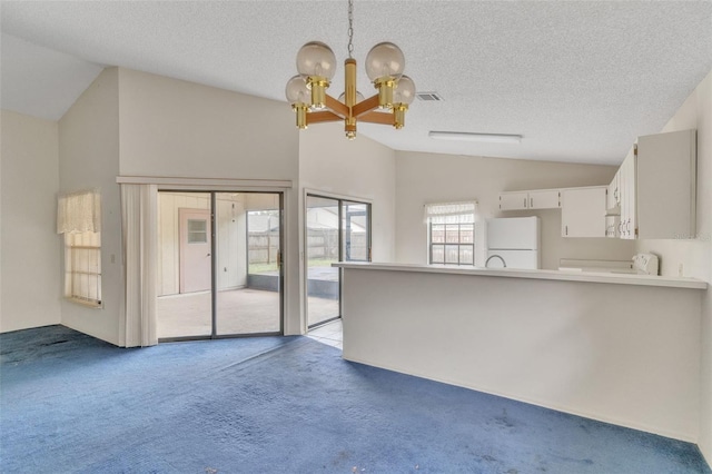 unfurnished living room featuring a notable chandelier, light colored carpet, a textured ceiling, and vaulted ceiling