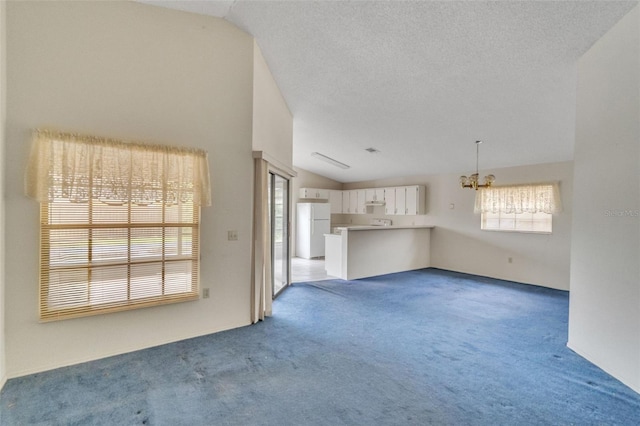 unfurnished living room featuring a textured ceiling, light carpet, and vaulted ceiling