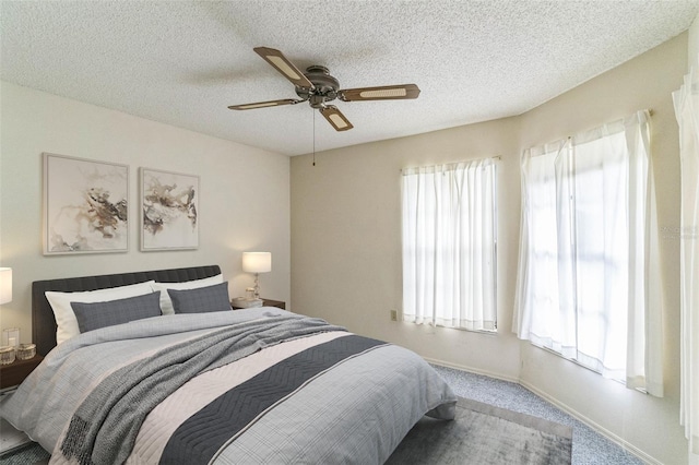 carpeted bedroom featuring ceiling fan and a textured ceiling