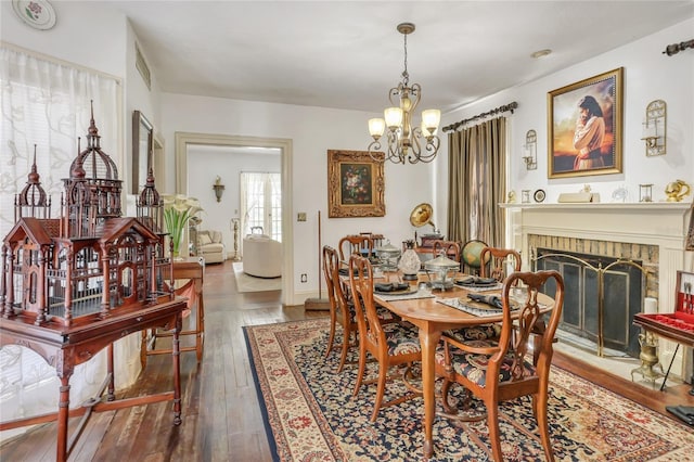 dining space with a fireplace, dark hardwood / wood-style flooring, and a notable chandelier