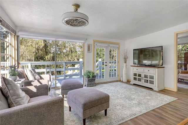 living room with french doors, light hardwood / wood-style flooring, and a textured ceiling