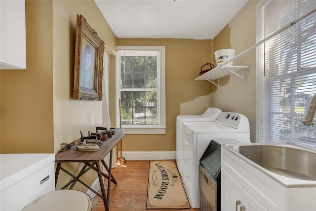 laundry area featuring sink, washer and dryer, and light hardwood / wood-style floors