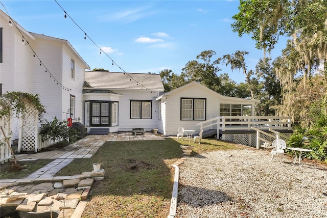 rear view of property featuring a deck, a lawn, and a patio