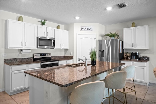 kitchen featuring stainless steel appliances, sink, a center island with sink, and white cabinets