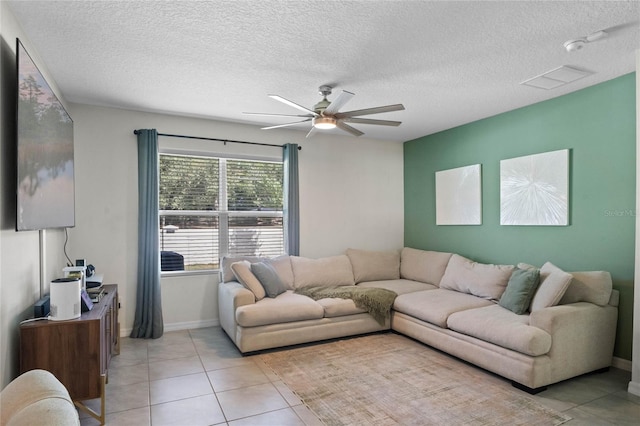 living room with a textured ceiling, ceiling fan, and light tile patterned flooring